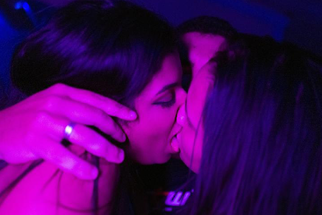 duas mulheres se beijando em uma casa de swing com clima de liberdade e respeito