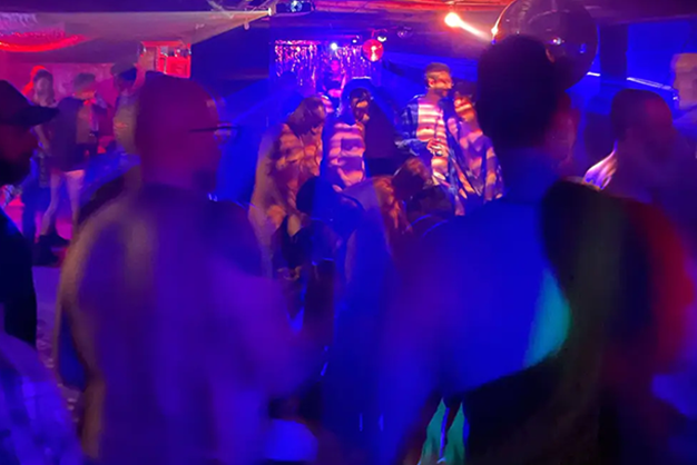 grupo de pessoas curtindo uma balada swing com luzes coloridas e clima de descontração