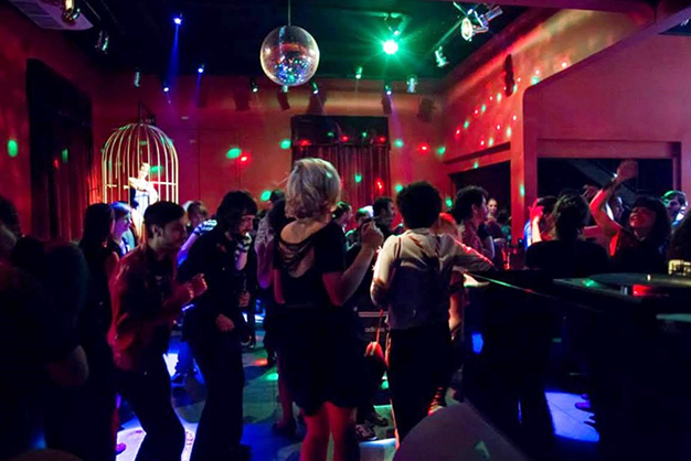 Área interna de casa de swing com iluminação e pessoas conversando